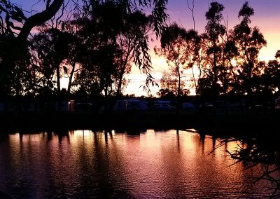 Stunning sunset reflection on a tranquil lake at Stawell Hotel Motel Accommodation, framed by trees, creating a picturesque evening atmosphere