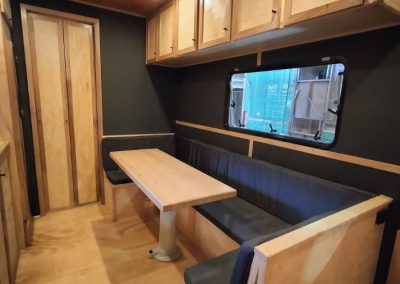 Interior dining area of a caravan with a table and comfortable seating, featuring wooden cabinets and large windows, ideal for meals and relaxation at Stawell Hotel Motel Accommodation