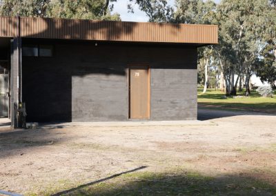 Close-up view of the ensuite accommodation at Stawell Hotel Motel, featuring the entrance door numbered 79, with a modern design, surrounded by a serene outdoor setting and tall trees in the background