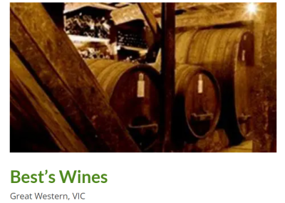 Interior view of Best's Wines winery in Great Western, VIC, featuring traditional wooden barrels lined up against rustic wooden beams, highlighting the rich heritage of winemaking in the region