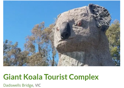 The Giant Koala Tourist Complex at Dadswells Bridge, VIC, featuring a towering concrete sculpture of a koala with large eyes and detailed features, surrounded by lush trees. This iconic landmark attracts visitors for photos and sightseeing in a picturesque rural setting
