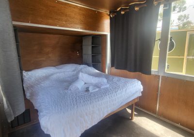 Cozy interior of a brown caravan with a neatly made double bed and soft lighting, perfect for a relaxing stay at Stawell Hotel Motel Accommodation