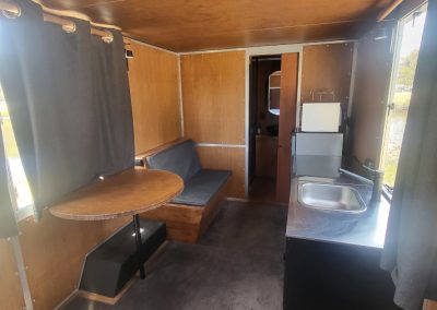 Spacious interior of a brown caravan featuring a dining area, kitchenette with sink, and seating, providing comfort and convenience at Stawell Hotel Motel Accommodation