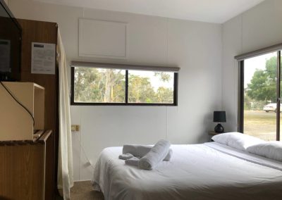 Bright cabin bedroom with a comfortable double bed, large windows, and a flat-screen TV at Stawell Hotel Motel Accommodation