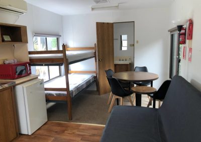 Spacious cabin interior featuring bunk beds, a dining table, kitchenette, and seating area at Stawell Hotel Motel Accommodation