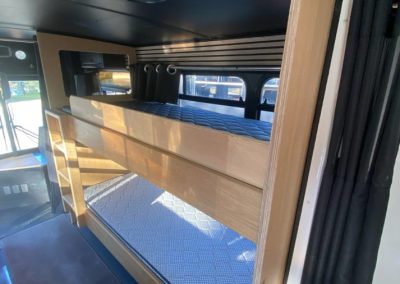 Interior of a converted bus accommodation featuring built-in wooden bunk beds with a skylight at Stawell Hotel Motel Accommodation