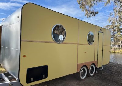 Exterior of a yellow, modern-style caravan with round windows parked near a lakeside at Stawell Hotel Motel Accommodation